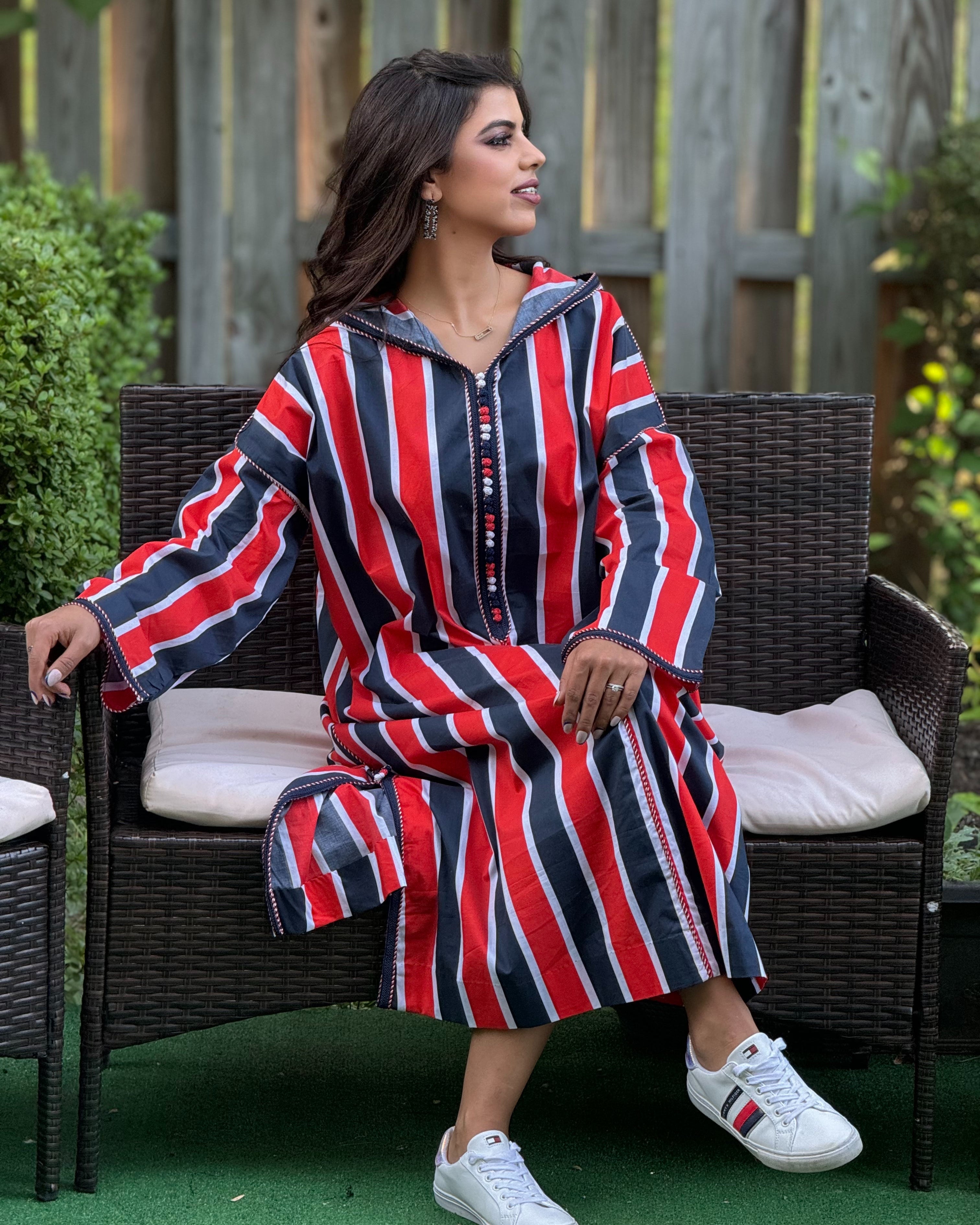 Woman wearing a red, white, and blue striped dress sitting on a wicker chair outdoors.