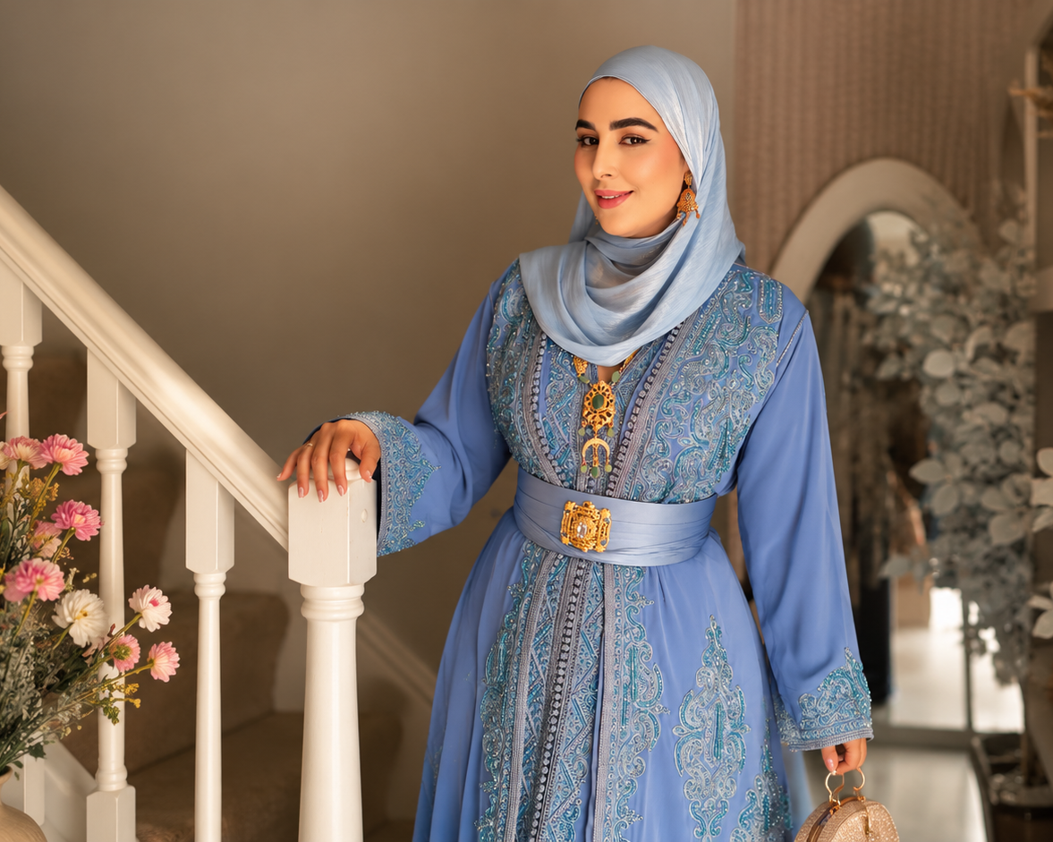 Woman in a blue traditional outfit standing on a staircase with decorative plants around.